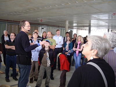 Baustellenführung "Bildung konsumieren" – Helmut Reitter führt durch das Nahversorgungszentrum "Q-West" und  "BRG in der Au"